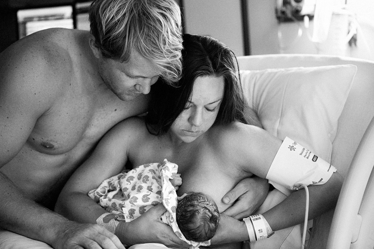 black and white Los Angeles birth photo of a husband and wife doing skin to skin bonding while trying for that first latch.