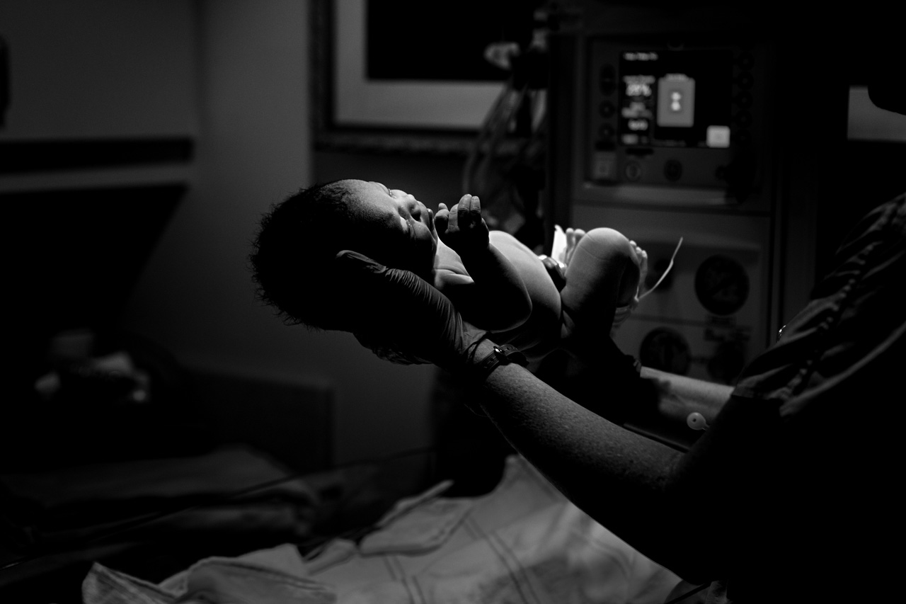 Black and white birth photo of a newborn baby is held by a doctor