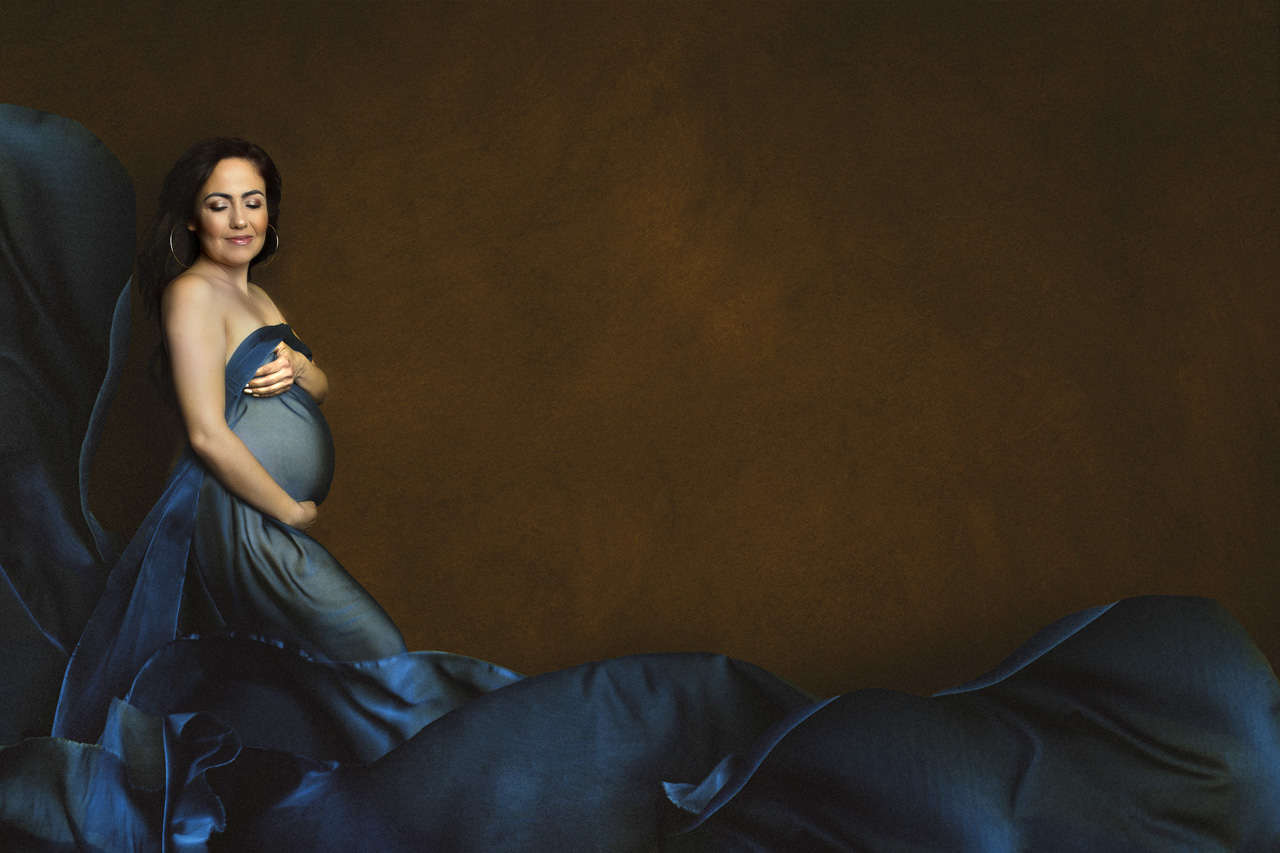 Color maternity portrait with blue silk fabric flowing