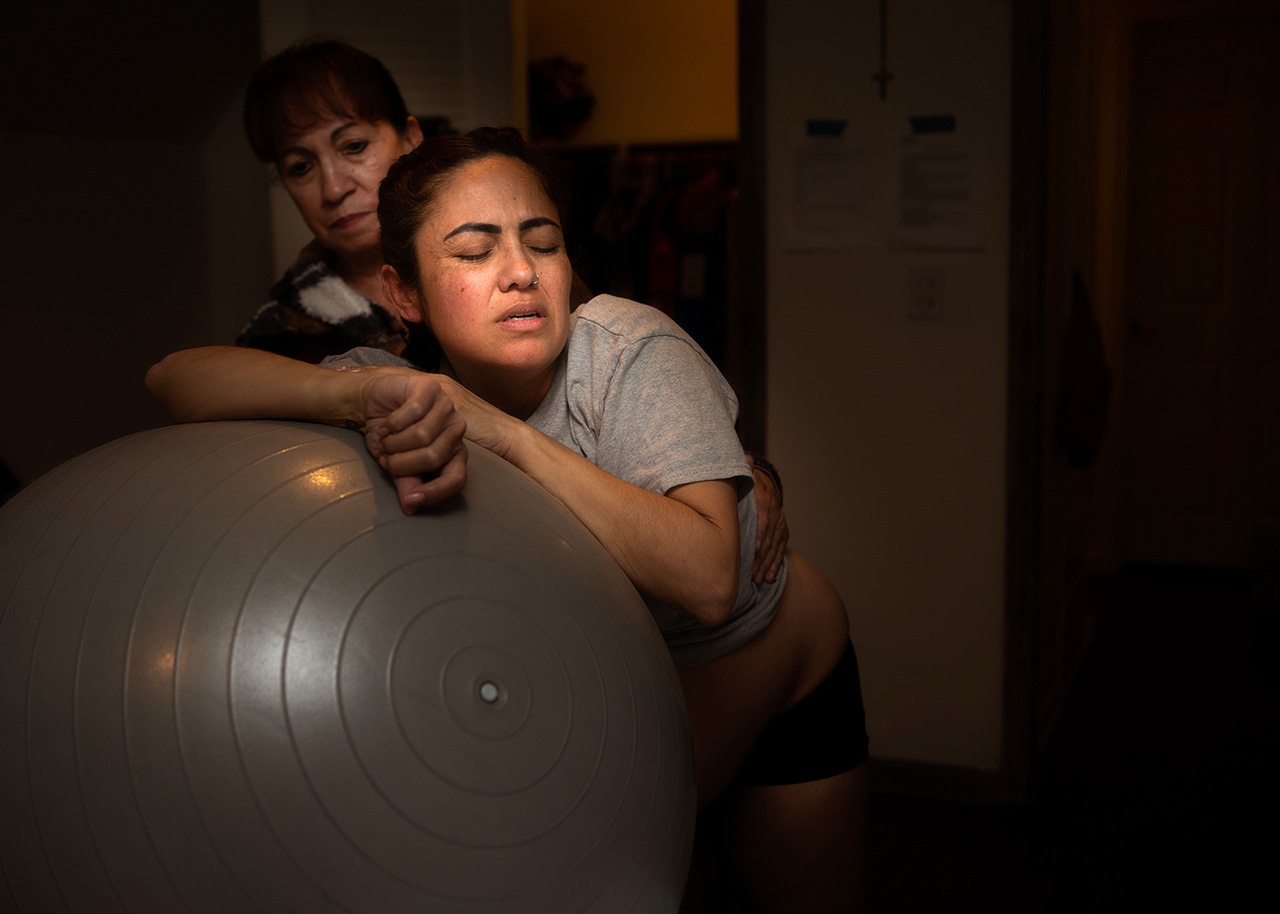 Color birth photo of a mother laboring on a birth ball by Los Angeles birth photographer, Leona Darnell