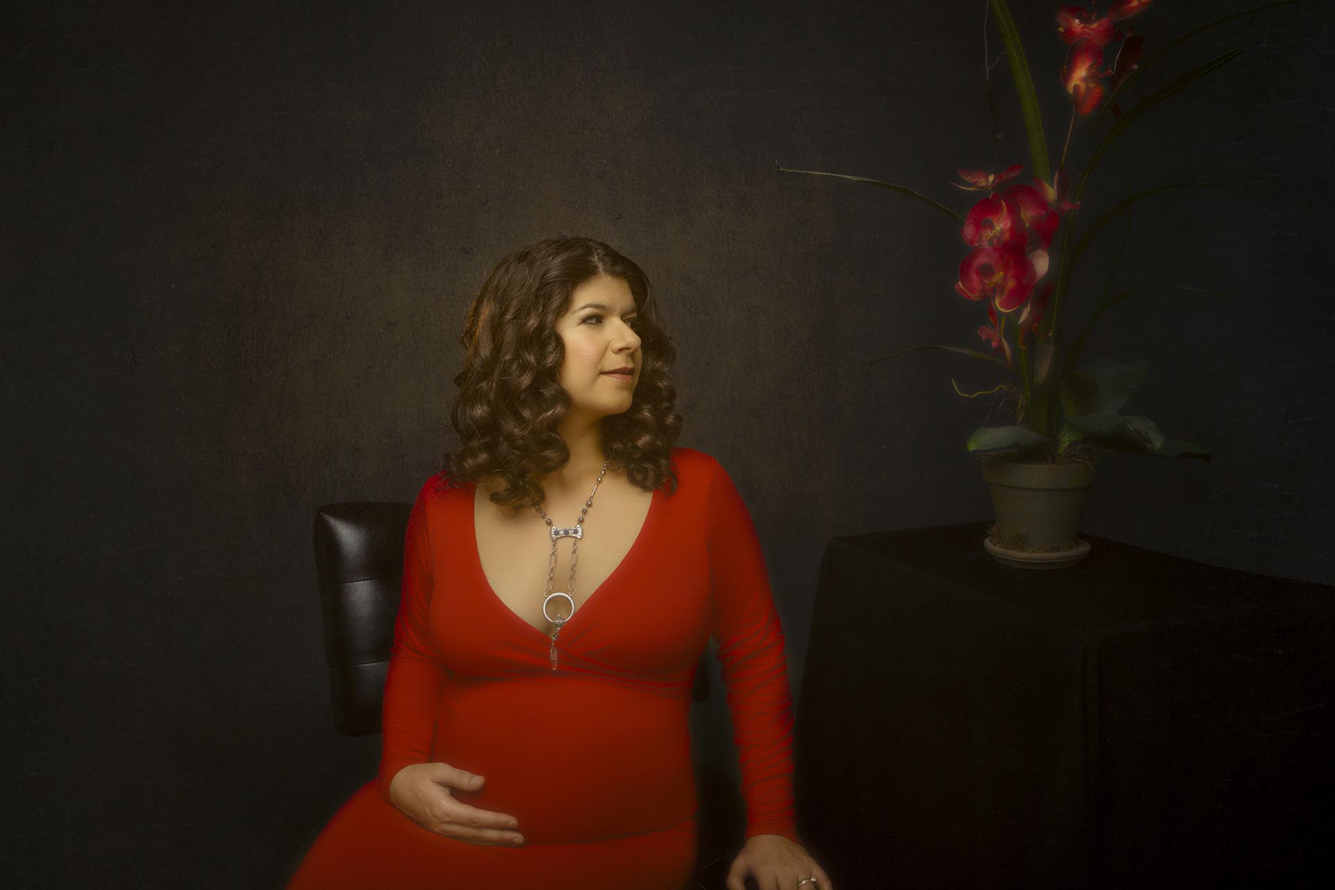 Color maternity portrait of a woman wearing a red maternity dress