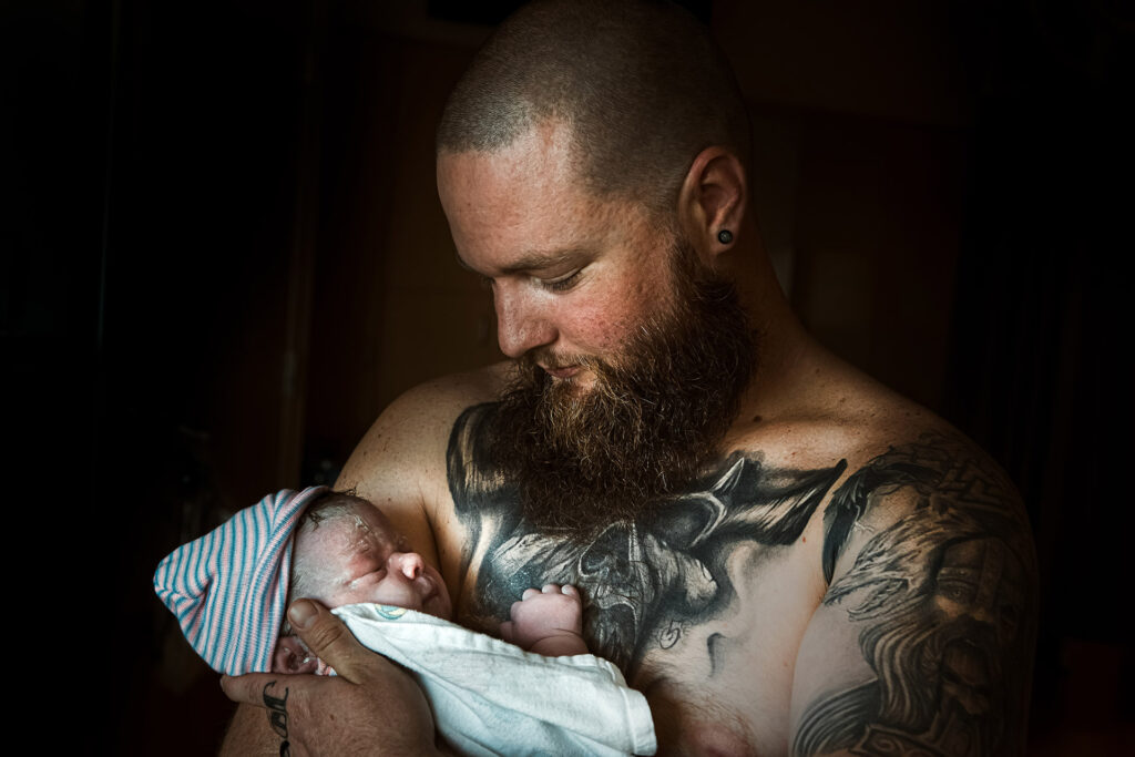 Los Angeles Birth and maternity photography postpartum image of a father holding his newborn daughter for the first time by birth photographer Leona Darnell