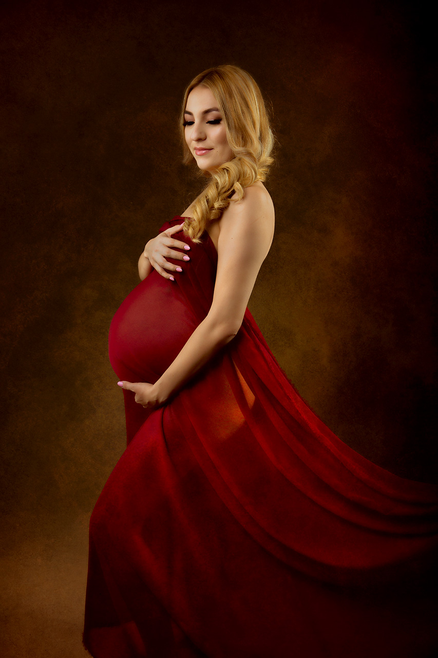 color maternity portrait of a blond woman wrapped in red material by Birth and Beauty