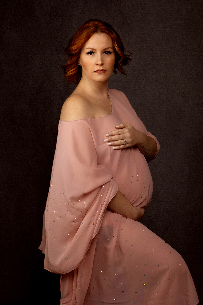 color maternity photo of a red headed woman in a pink dress by Birth and Beauty