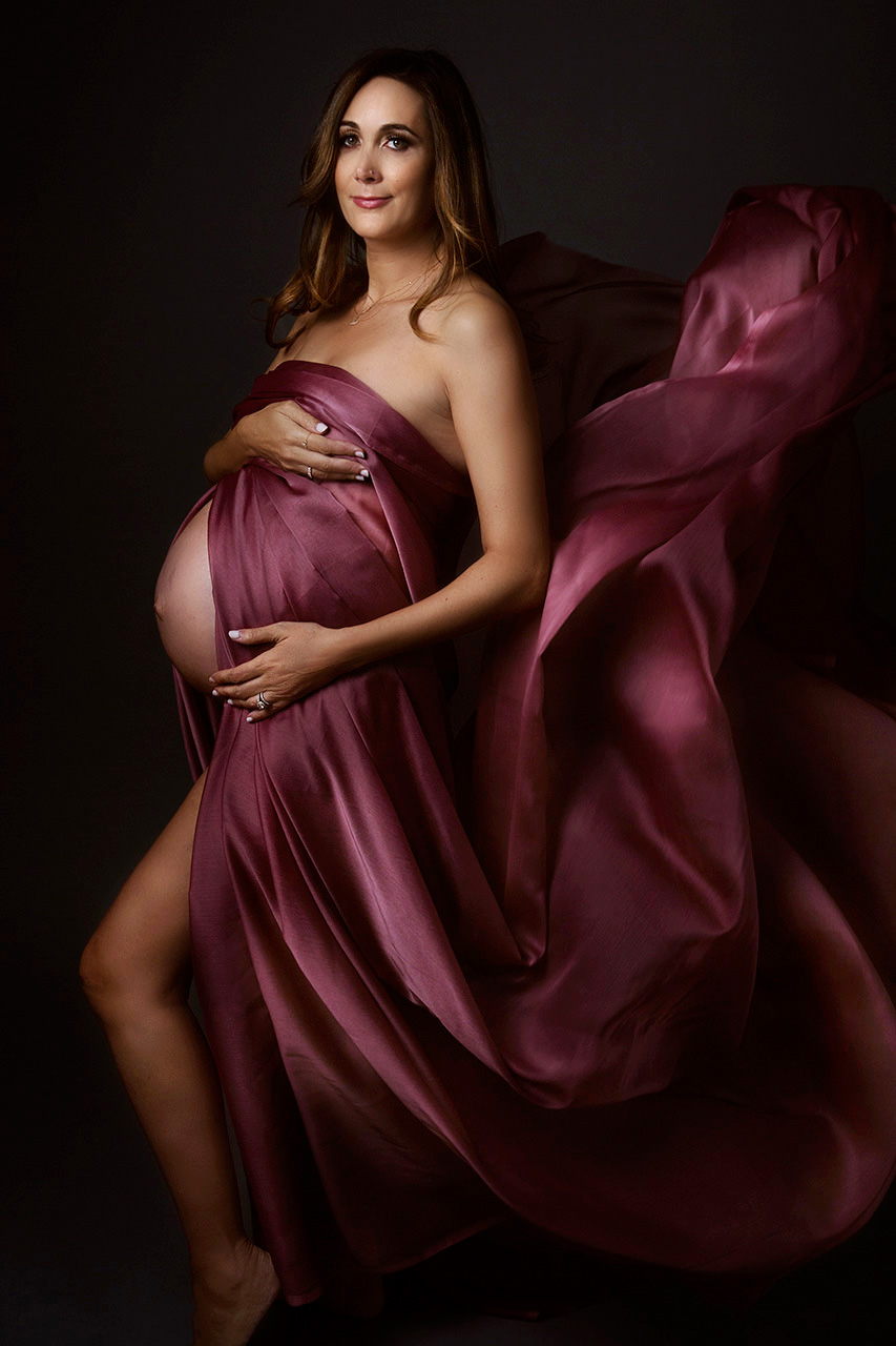 los angeles maternity portrait of a woman with mauve material draped around her.