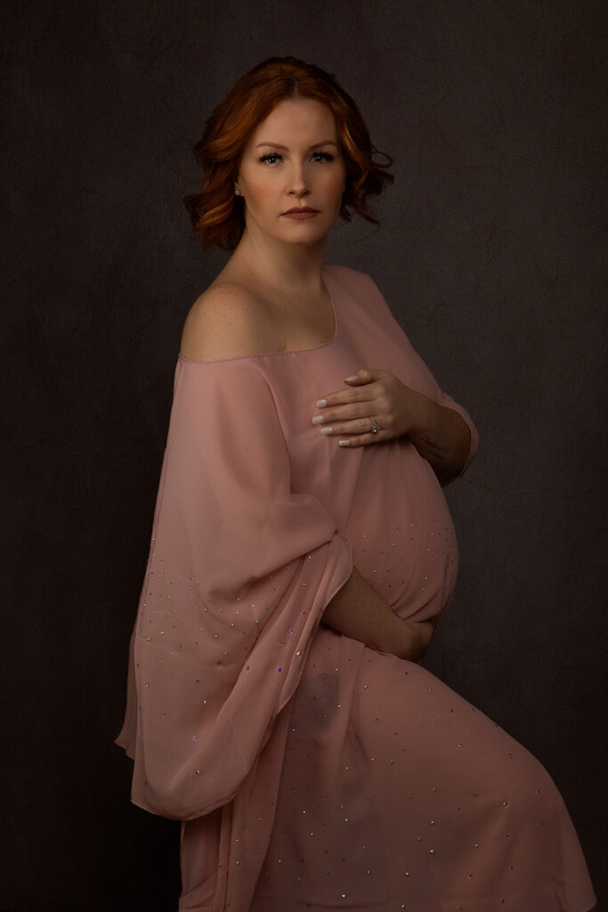 Fine art maternity portrait of a red haird woman with pink chiffon wrapped around her by Birth and Beauty