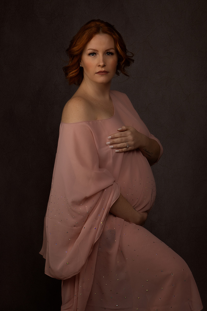 Fine art maternity portrait of a red haird woman with pink chiffon wrapped around her by Birth and Beauty