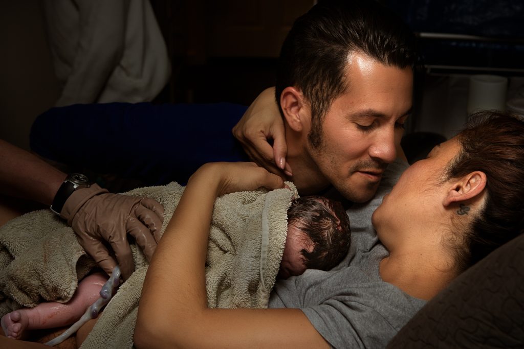 Color birth photo by Leona Darnell showing a mother and father right after birth kissing