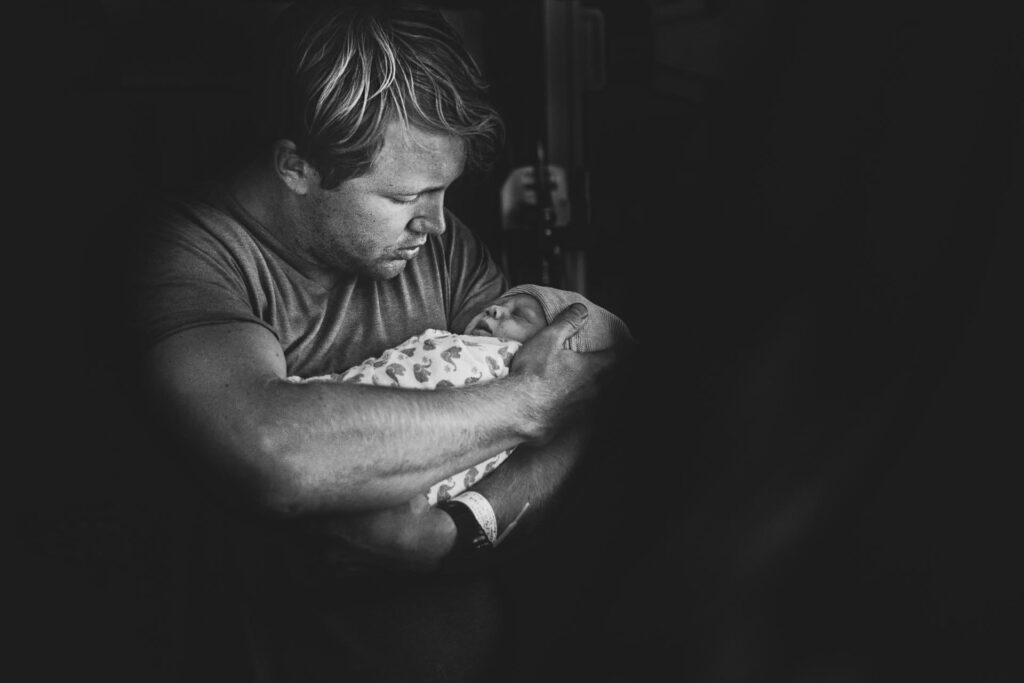 black and white birth photo of a dad holding his newborn daughter by Cedars Sinai birth photographer, Leona Darnell.