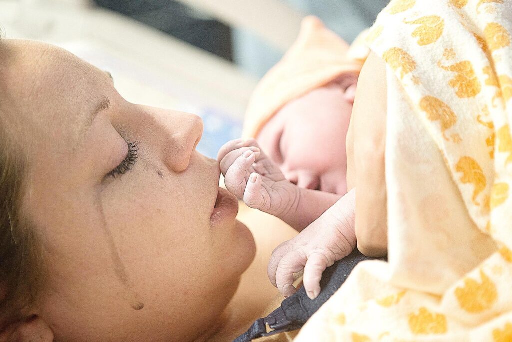 birth photo of a mom kissing her daughters hand by los angeles birth photographer, Leona Darnell