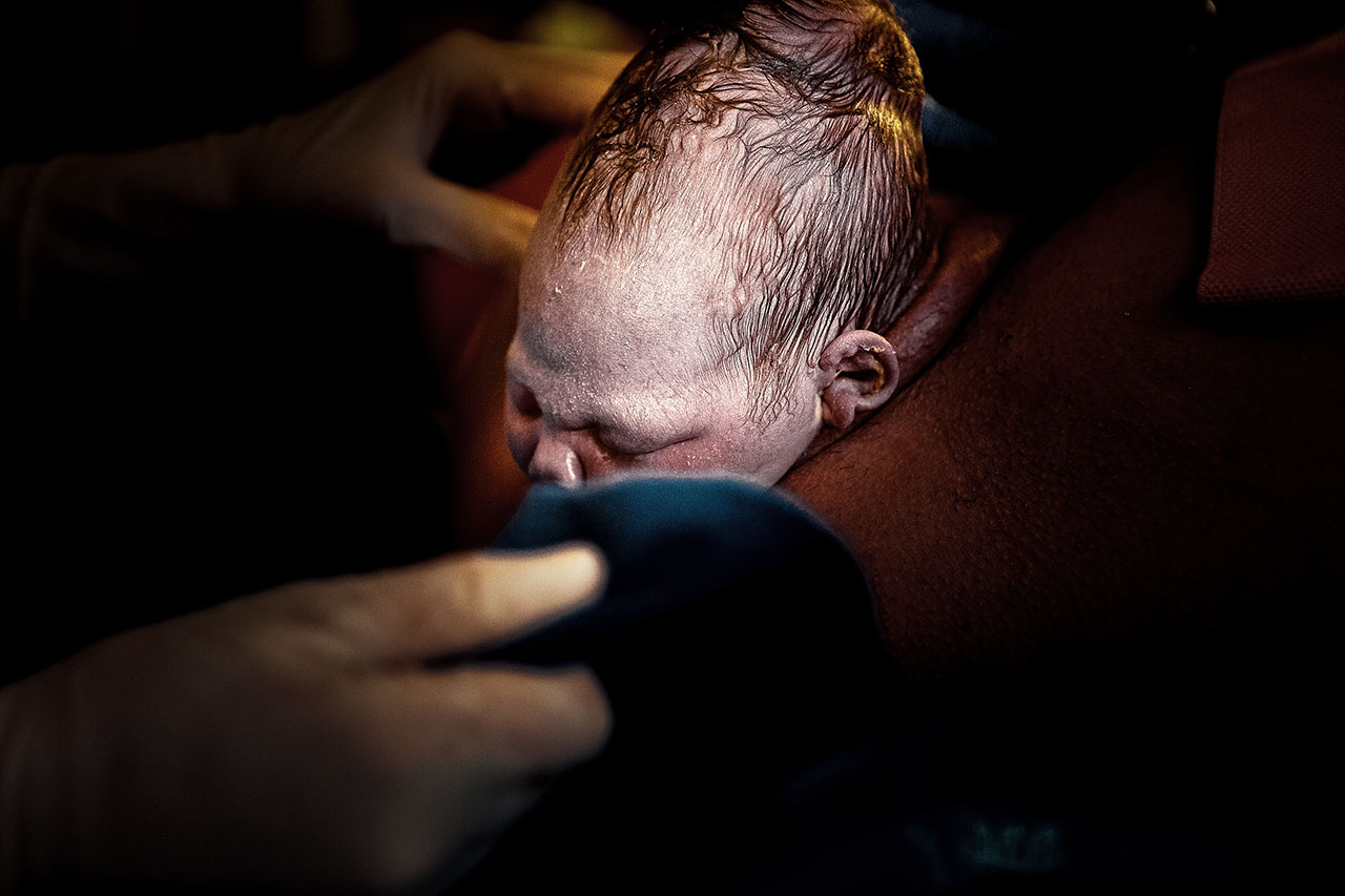 color birth photo of a baby with it's head out of mom's vagina by Santa Monica birth photographer, Leona Darnell