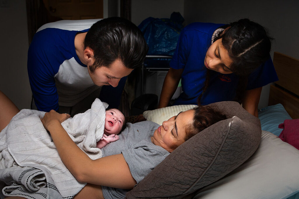 Color birth photo of the family looking at the newborn baby during a Los Angeles home birth.