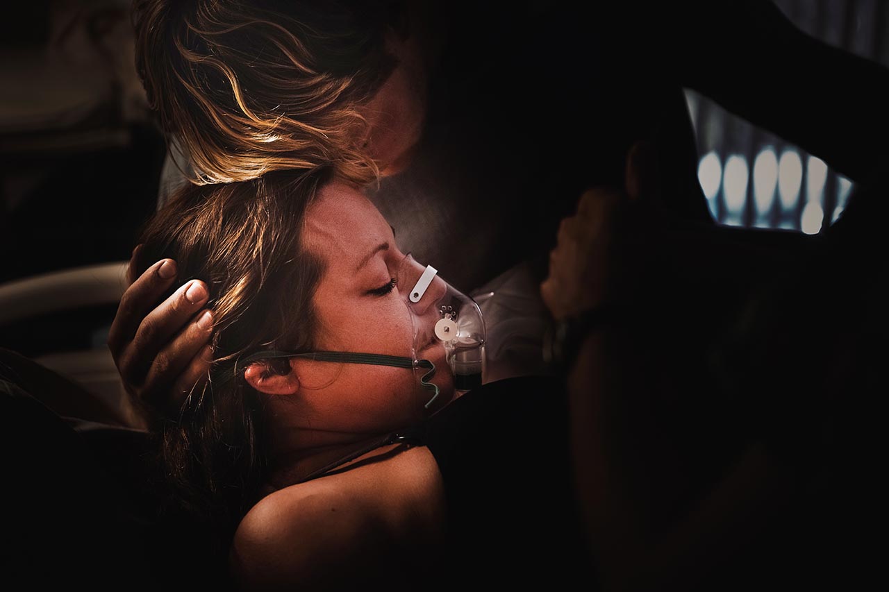 Color birth photo of a woman in labor being supported by her partner. Photo by Pasadena birth photographer, Leonba Darnell