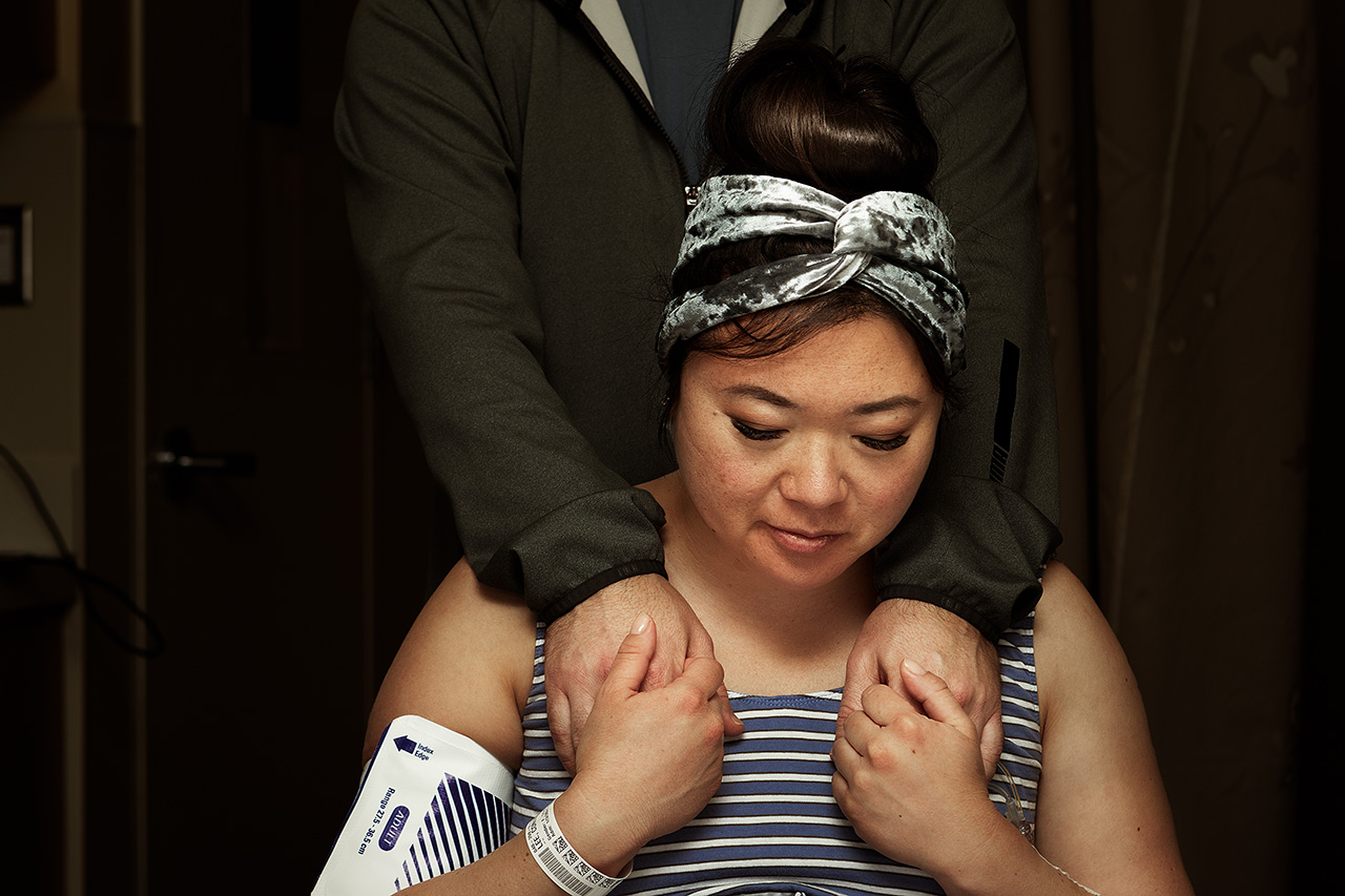 Color baith photo of a laboring mother holding her husband's hands.