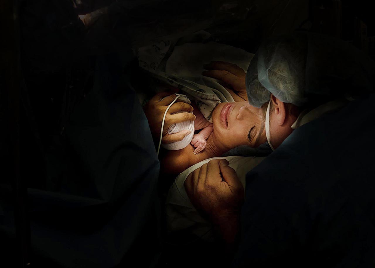 A mother holding her baby after a cesarean birth by Birth and Beauty photography