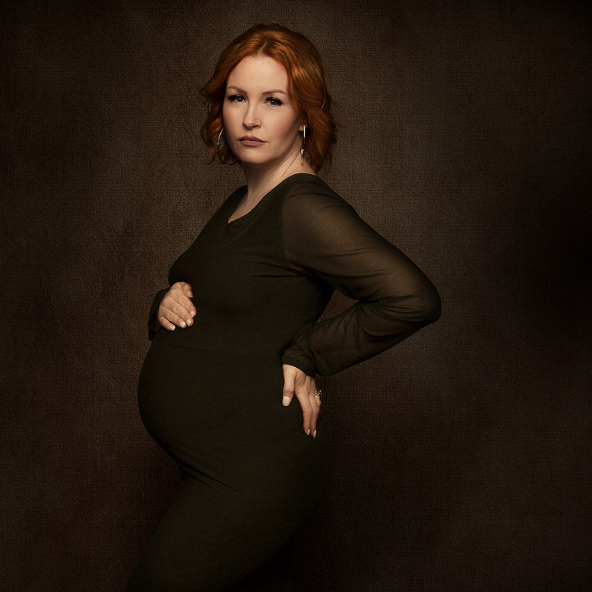 Maternity photo of a woman with red hair wearing a green dress by Leona Darnell