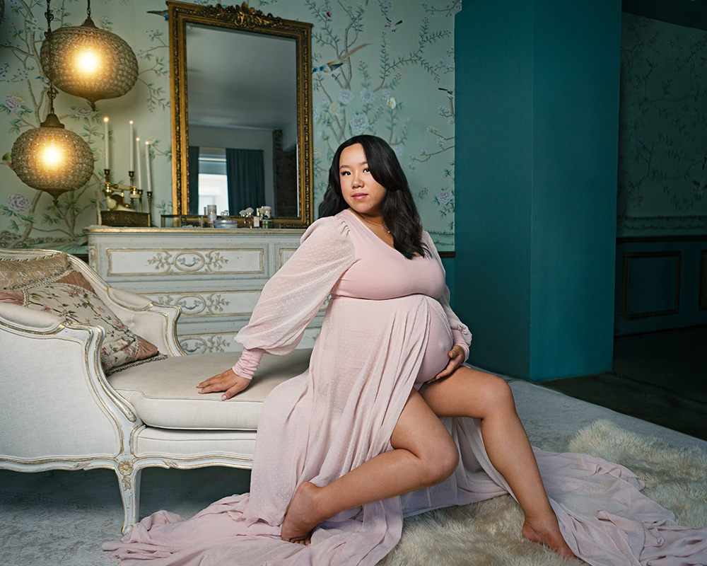 Maternity portrait by Leona Darnell showing a pregnant woman lounging in a pink dress.