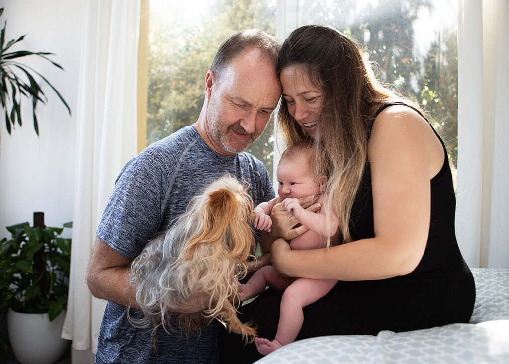 Lifestyle newborn image of a mother, father and newborn meeting the family dog by Leona Darnell