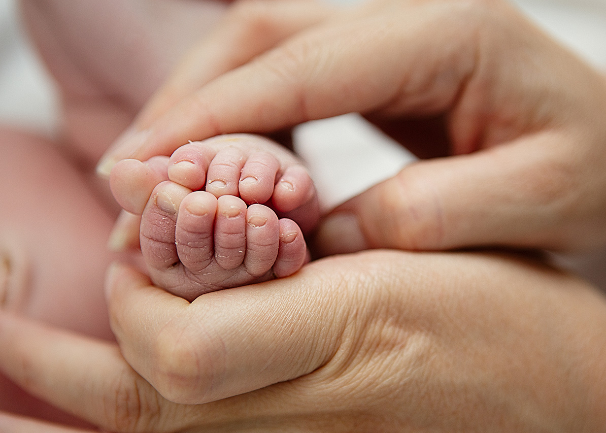 Lifestyle photo of a newborns toes while being held by his mother by Leona Darnell