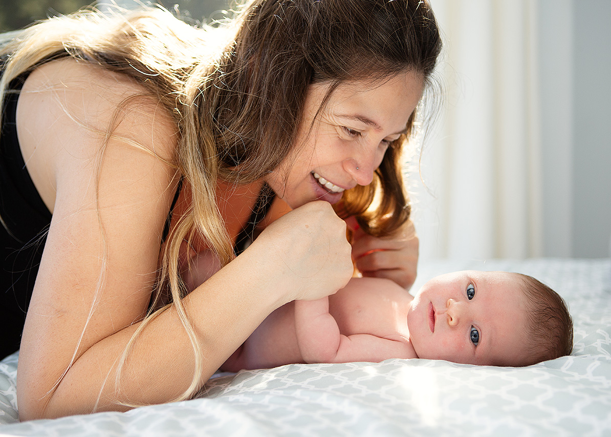Santa Monica lifestyle newborn photographer captures a mother smiling as baby looks at the camera.