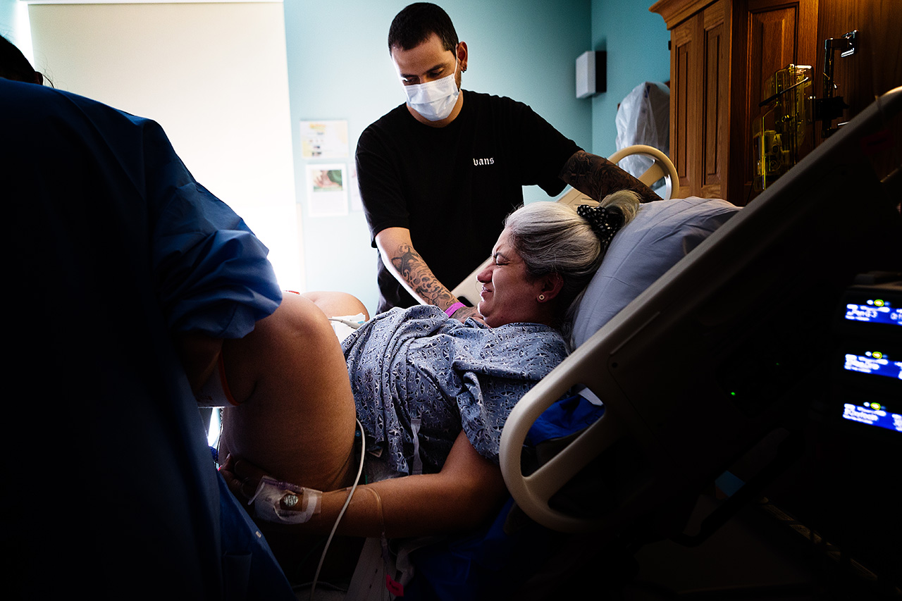 Color birth photo of a woman pushing while her husband holds her by Leona Darnell