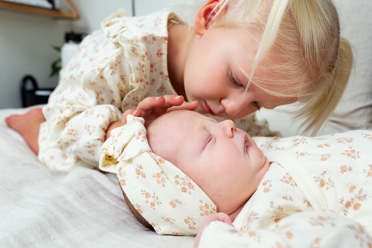 lifestyle newborn photo of a baby girl and her big sister in matching outfits