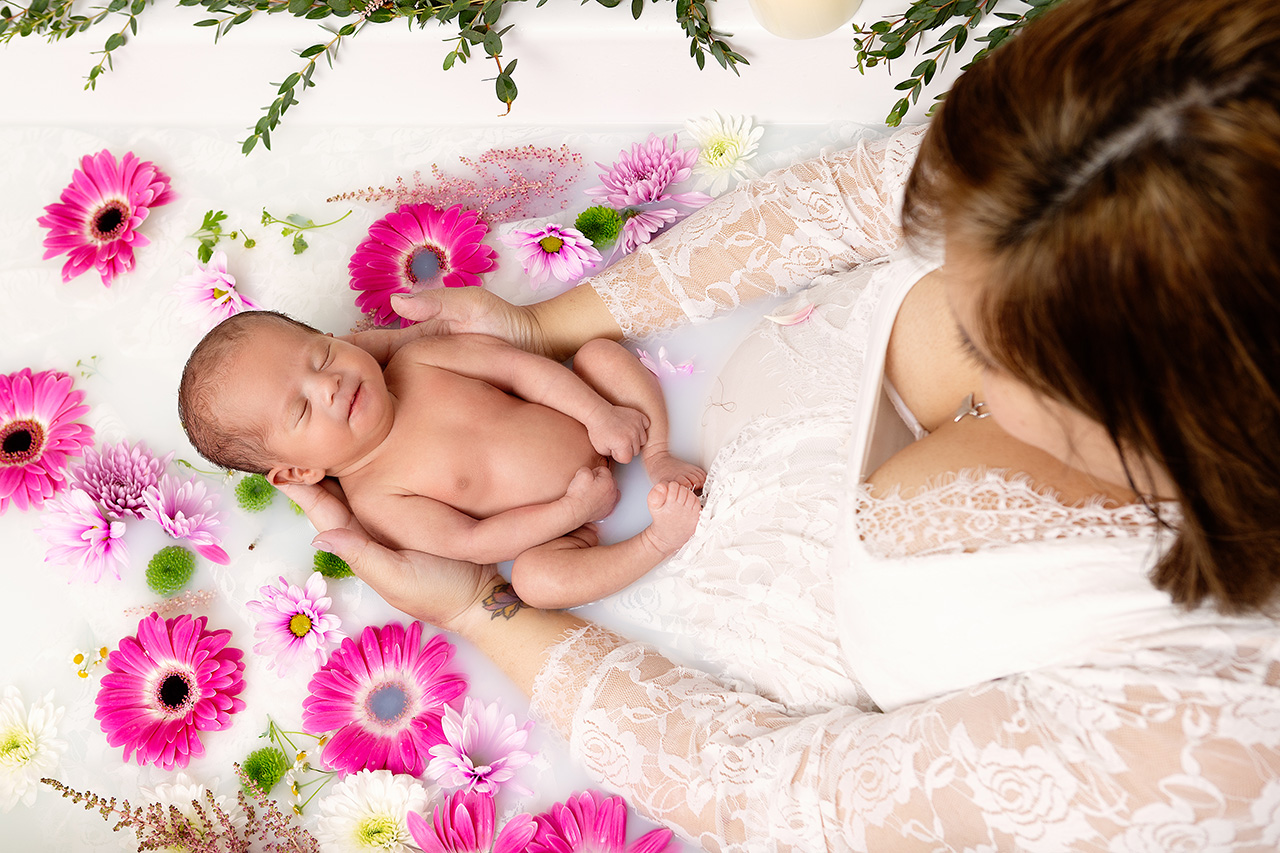 Newborn baby and mother in a milk bath with flowers