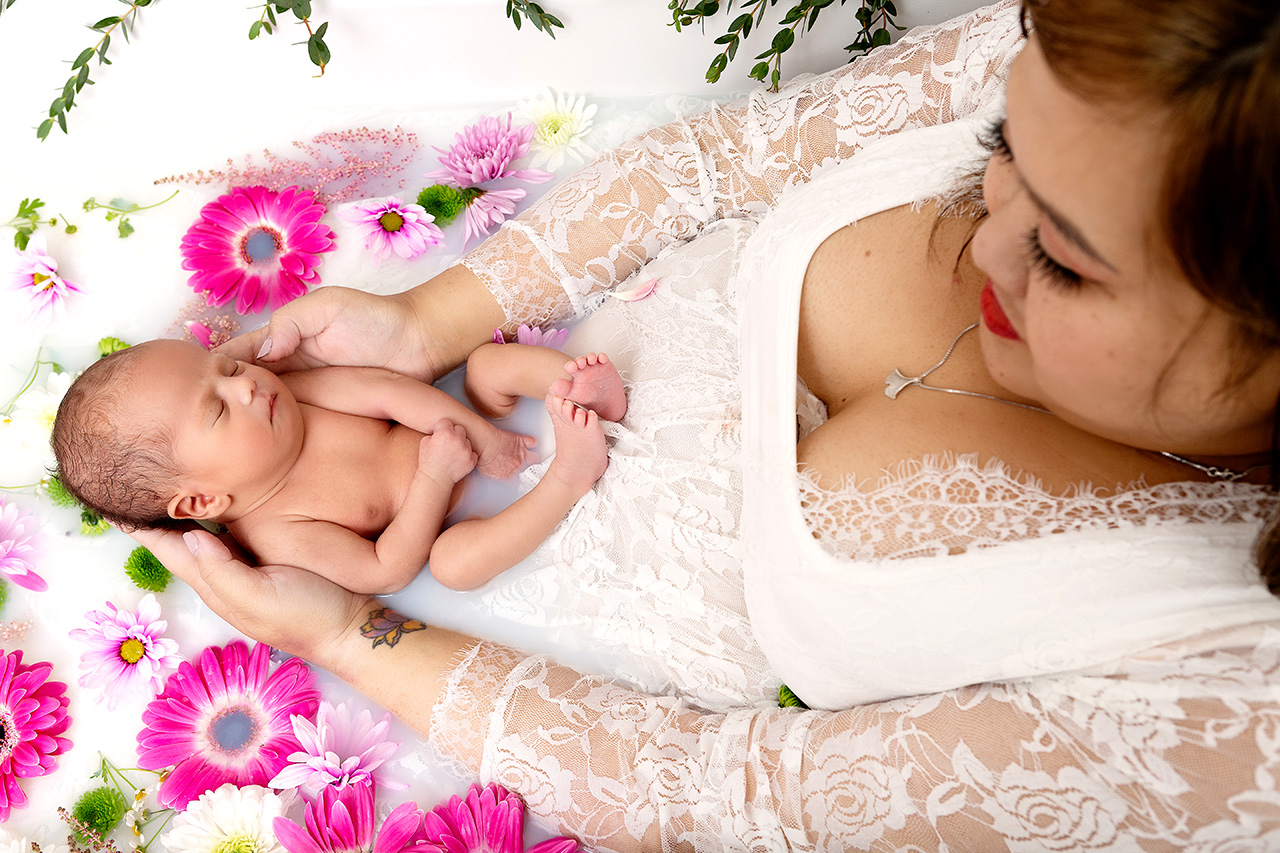 Newborn baby and mother in a milk bath with flowers