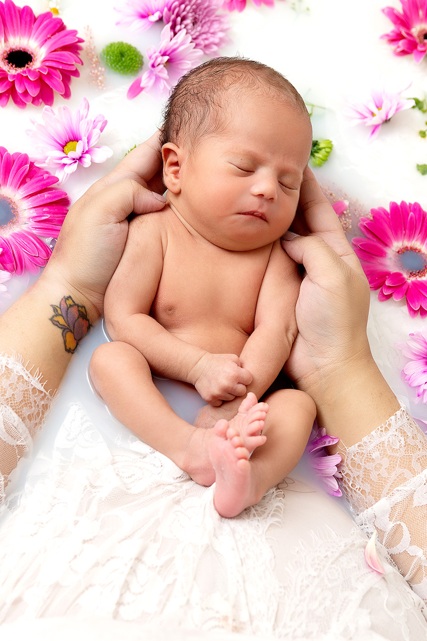 Newborn baby and mother in a milk bath with flowers