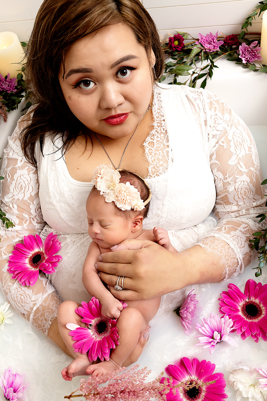 Newborn baby and mother in a milk bath with flowers