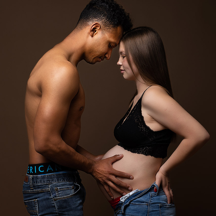 color maternity photo as a mother and the father holding her belly by birth photographer, Leona Darnell