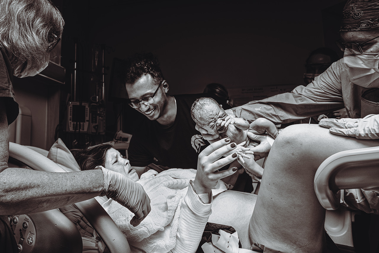 Black and white birth photo of a hospital birth in San Diego where a mother is seeing her baby for the first time.