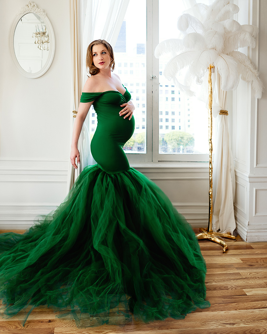 Maternity portrait of a woman in a tight green dress.