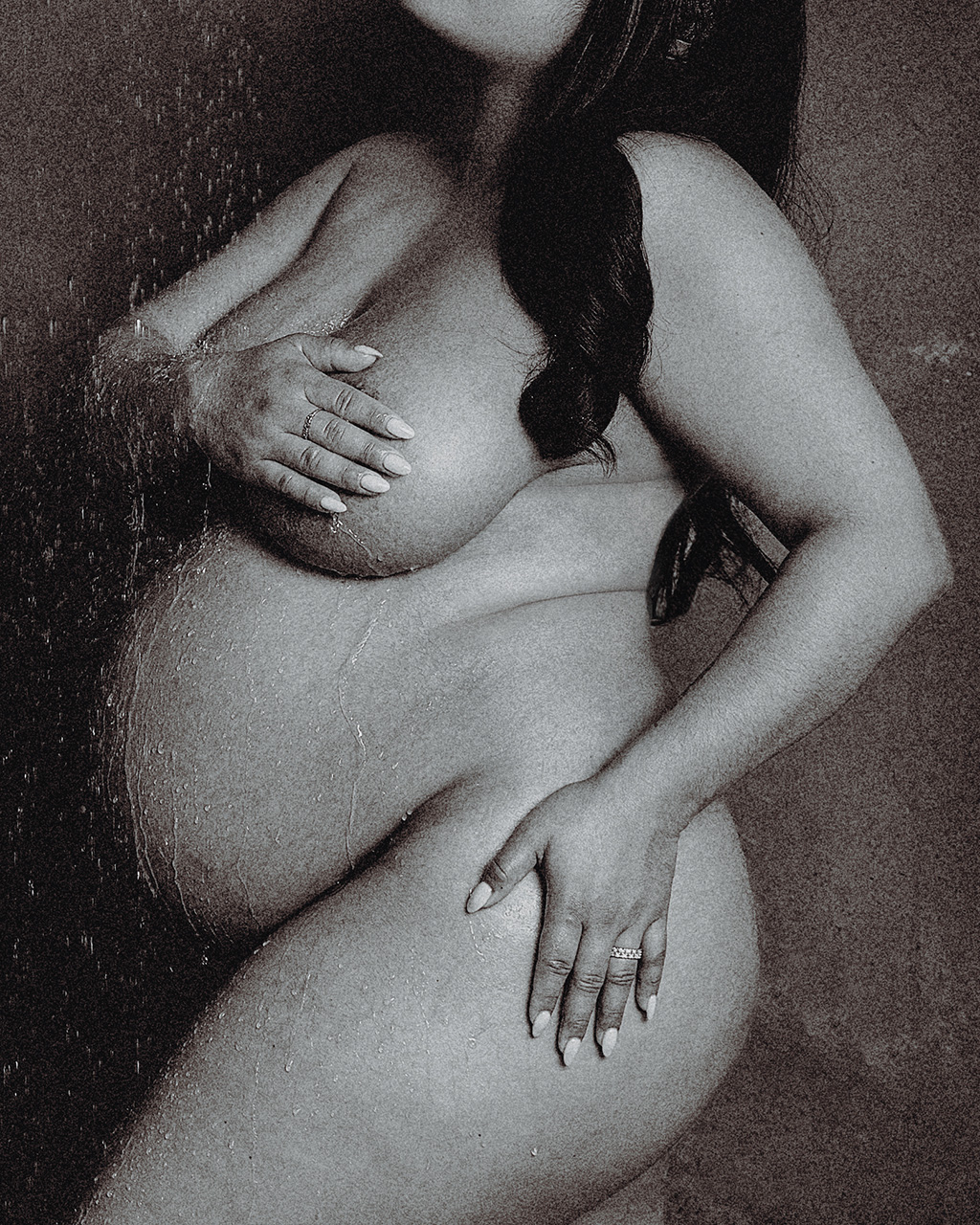 black and white maternity photo of a nude woman under the shower.