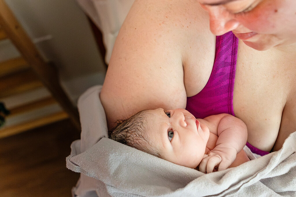 Birth story photo of a newborn baby looking at her mother by Birth photographer and labor doula, Leona Darnell