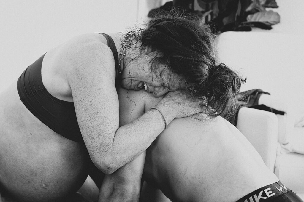 black and white birth photo of a woman being supported by her husband.