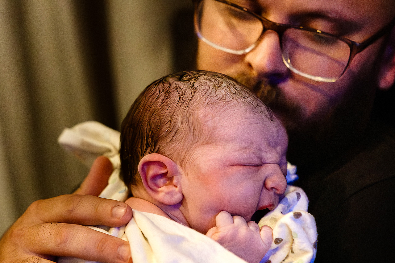 Color birth image by Leona Darnell of a dad holding his newborn daughter.