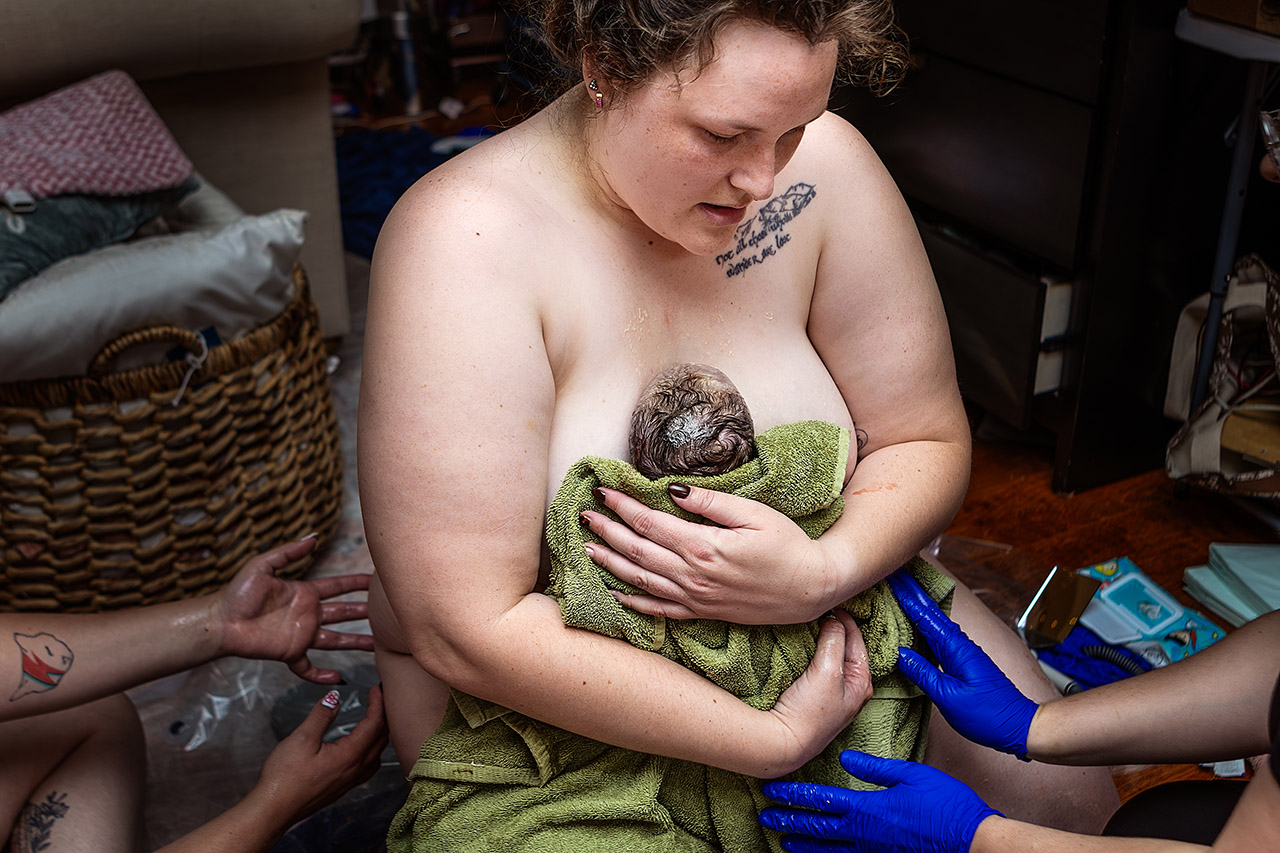 Birth photography capturing an intimate, emotional moment as a mother holds her newborn daughter for the first time, surrounded by warmth, connection, and love. Photo by Leona Darnell.