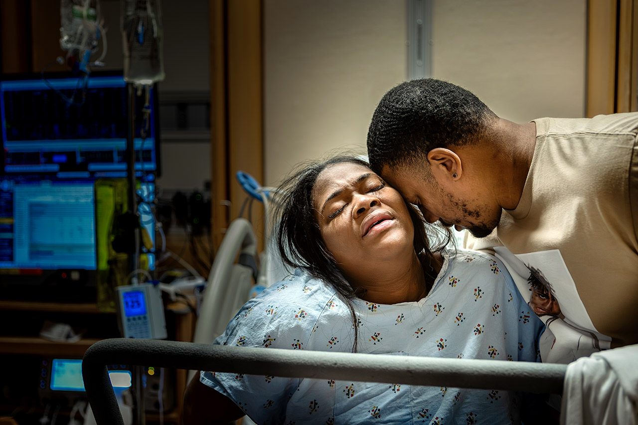 Father supporting his wife during labor at a Santa Monica hospital birth, captured by a Los Angeles birth photographer, Leona Darnell, during the birth of their second child.