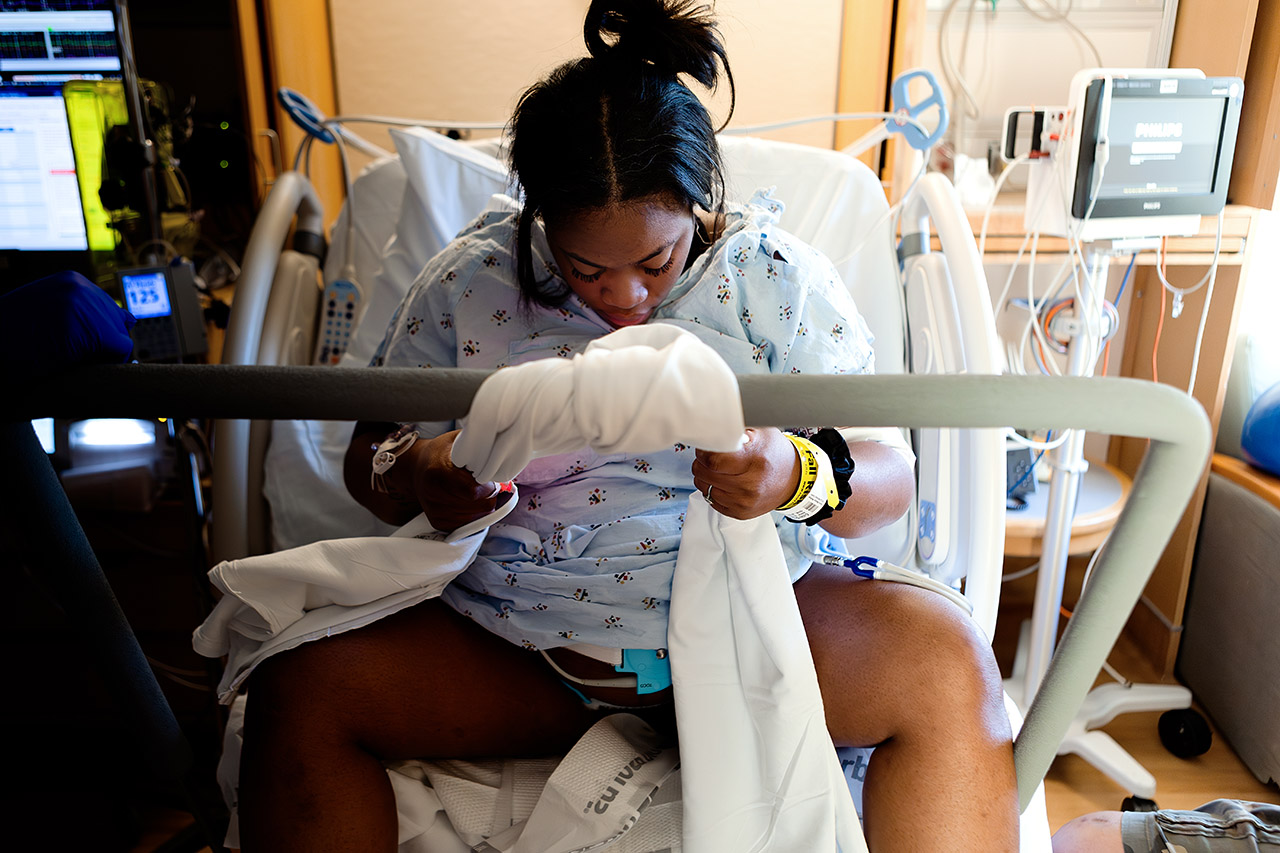 A mother holding on to a birth bar during labor in Santa Monica, as photographed by birth videographer, Leona Darnell.
