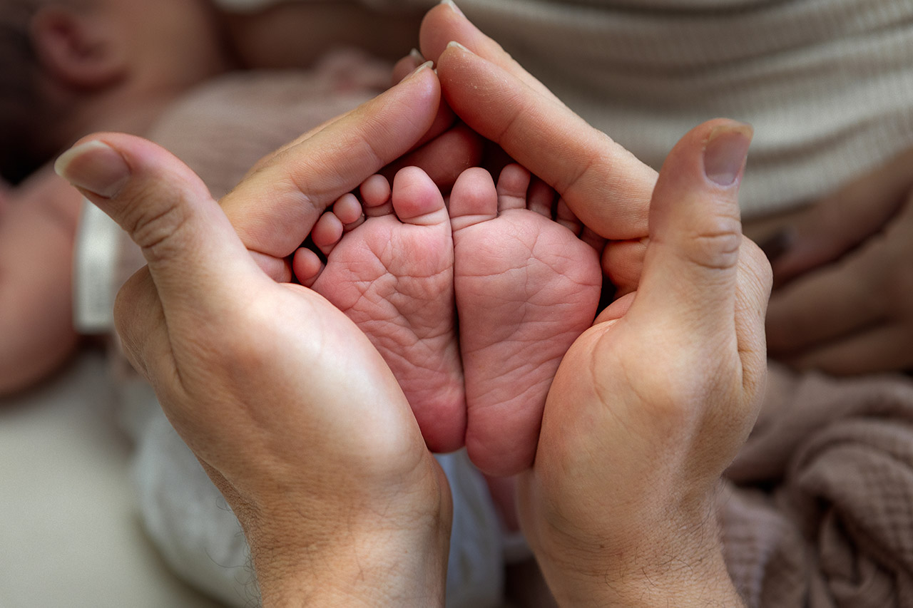 Newborn baby feet being held by her mother during a newborn session. Birth photography and birth videography by Leona Darnell. 