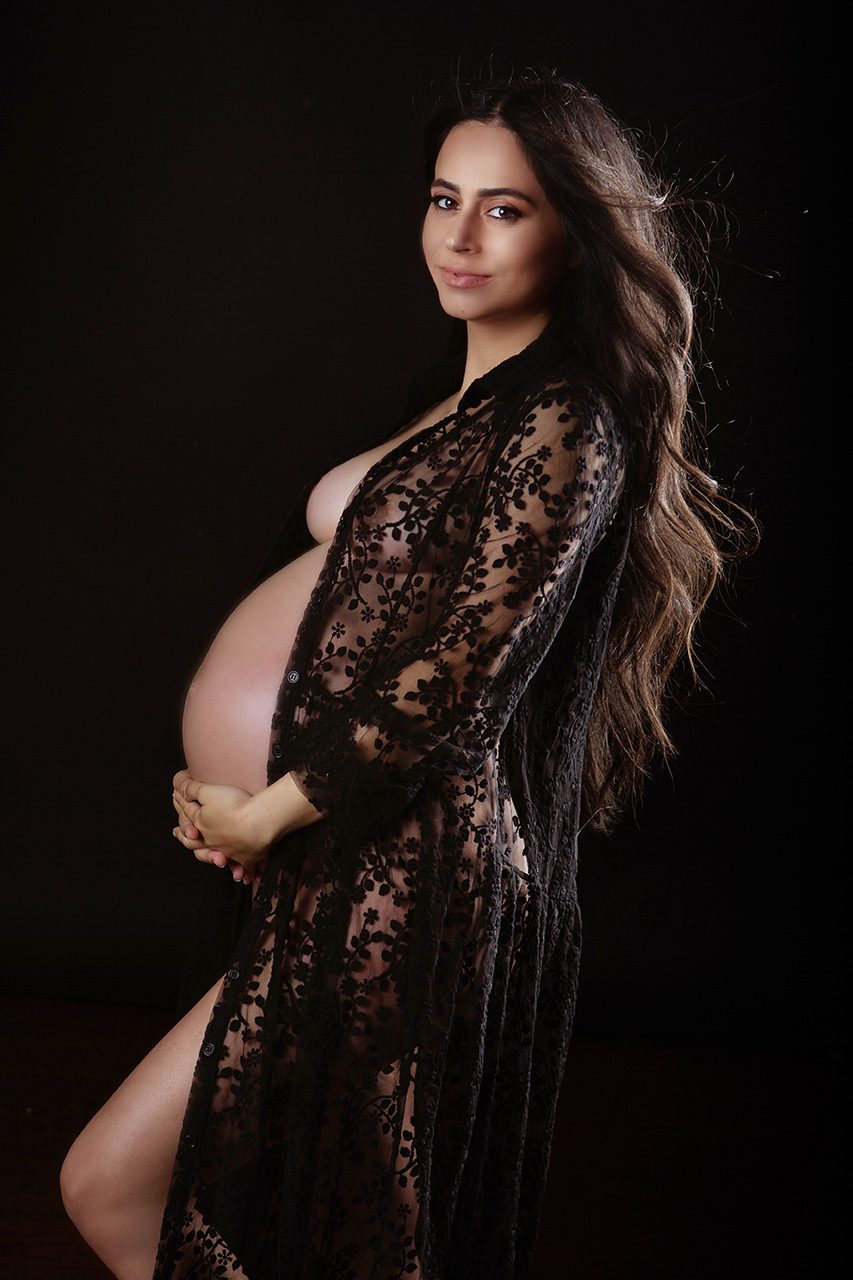 Pregnant woman wearing a black gown in a dramatic side-profile studio maternity session by Los Angeles birth and maternity photographer Leona Darnell.