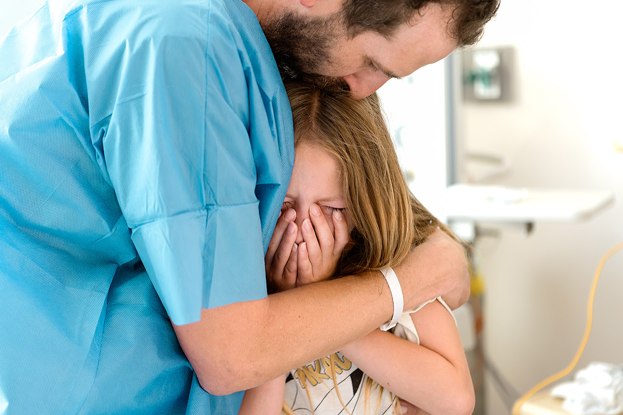 A Los Angeles birth photo of a little girl who witnessed her mother giving birth. The father is holding her while she cries. Photography by Birth and Beauty