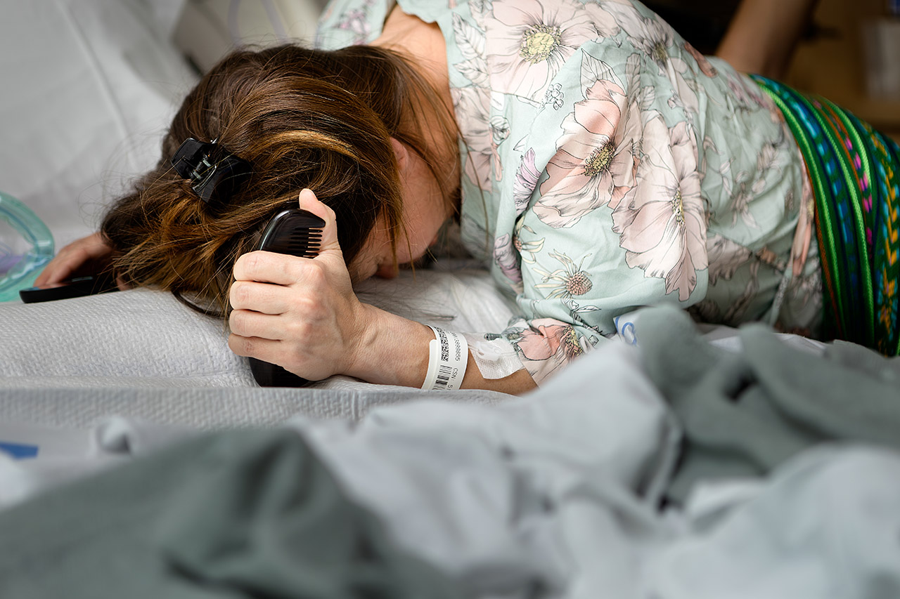 A Los Angeles hospital birth of a mother grasping tightly to a comb during a contraction. Photo by Leona Darnell and Birth and Beauty.